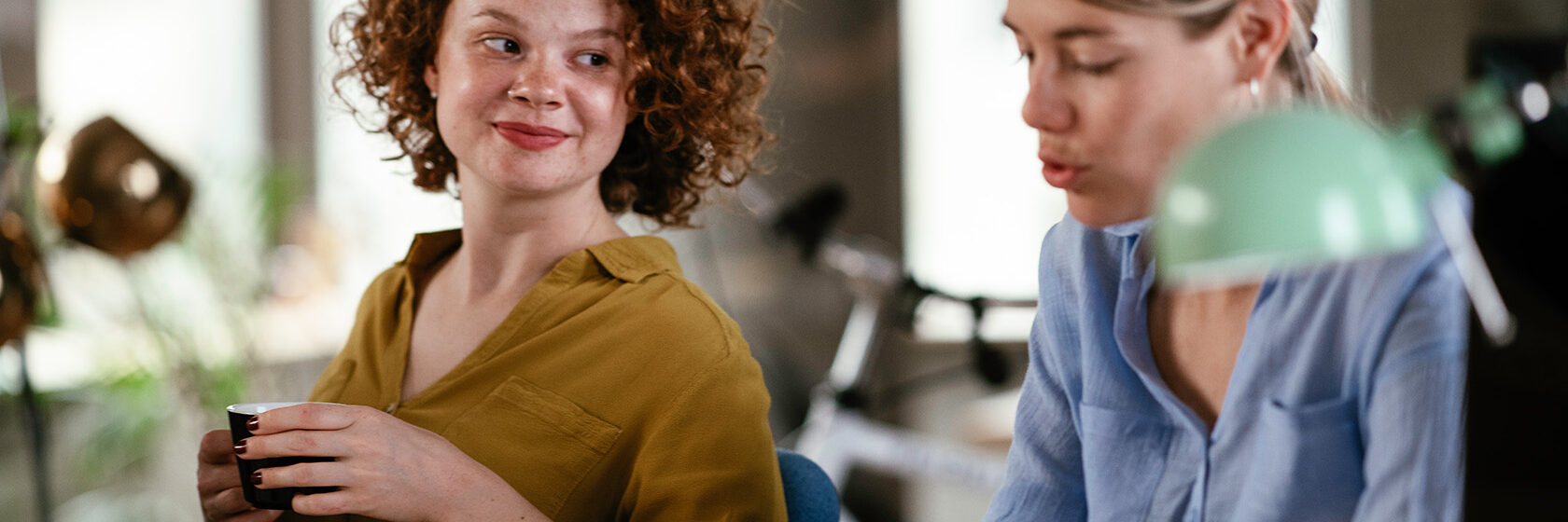 Två yngre kvinnor samtalar på ett kontor
