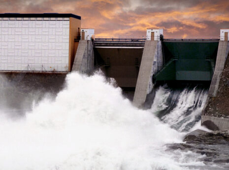 Vattenkraftverk med forsande vatten under dramatisk himmel.