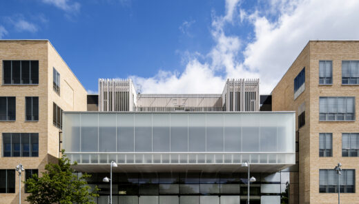 Modern byggnad med glasfasad och tegelväggar under en blå himmel.