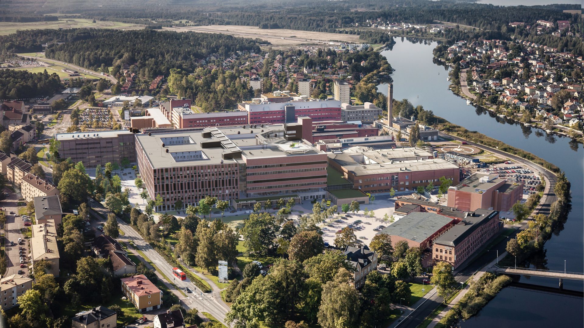 Flygfoto av Centralsjukhuset i Karlstad, omgiven av grönska och vatten.