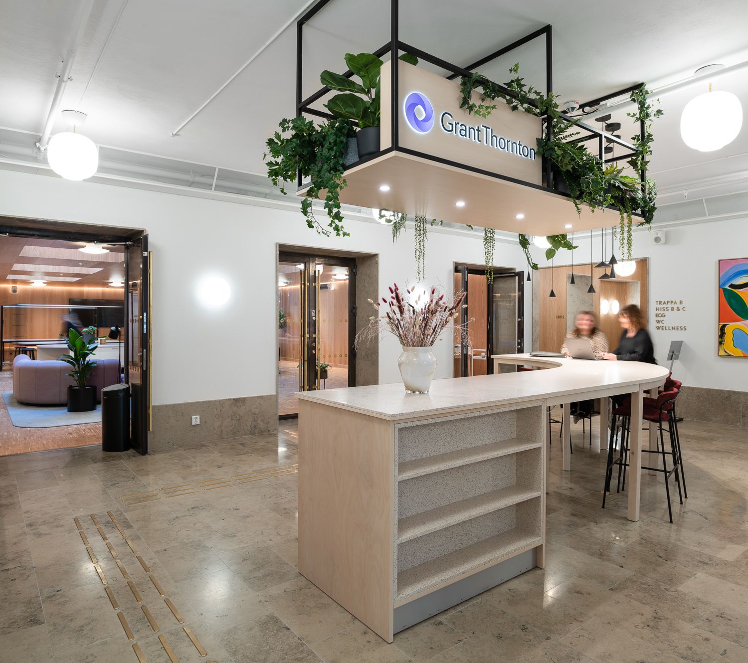 Modernt kontor med reception, växtdekorationer och bord med sittplatser hos Grant Thornton.