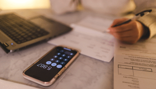 Miniräknare med räkningar under och en hand med en penna