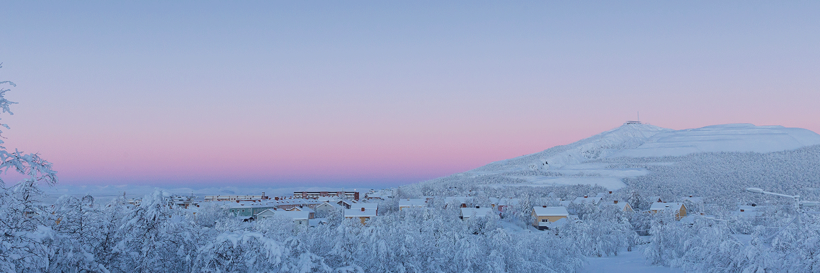 Vinterlandskap i gryningsljus med svagt rosa och gråblå toner