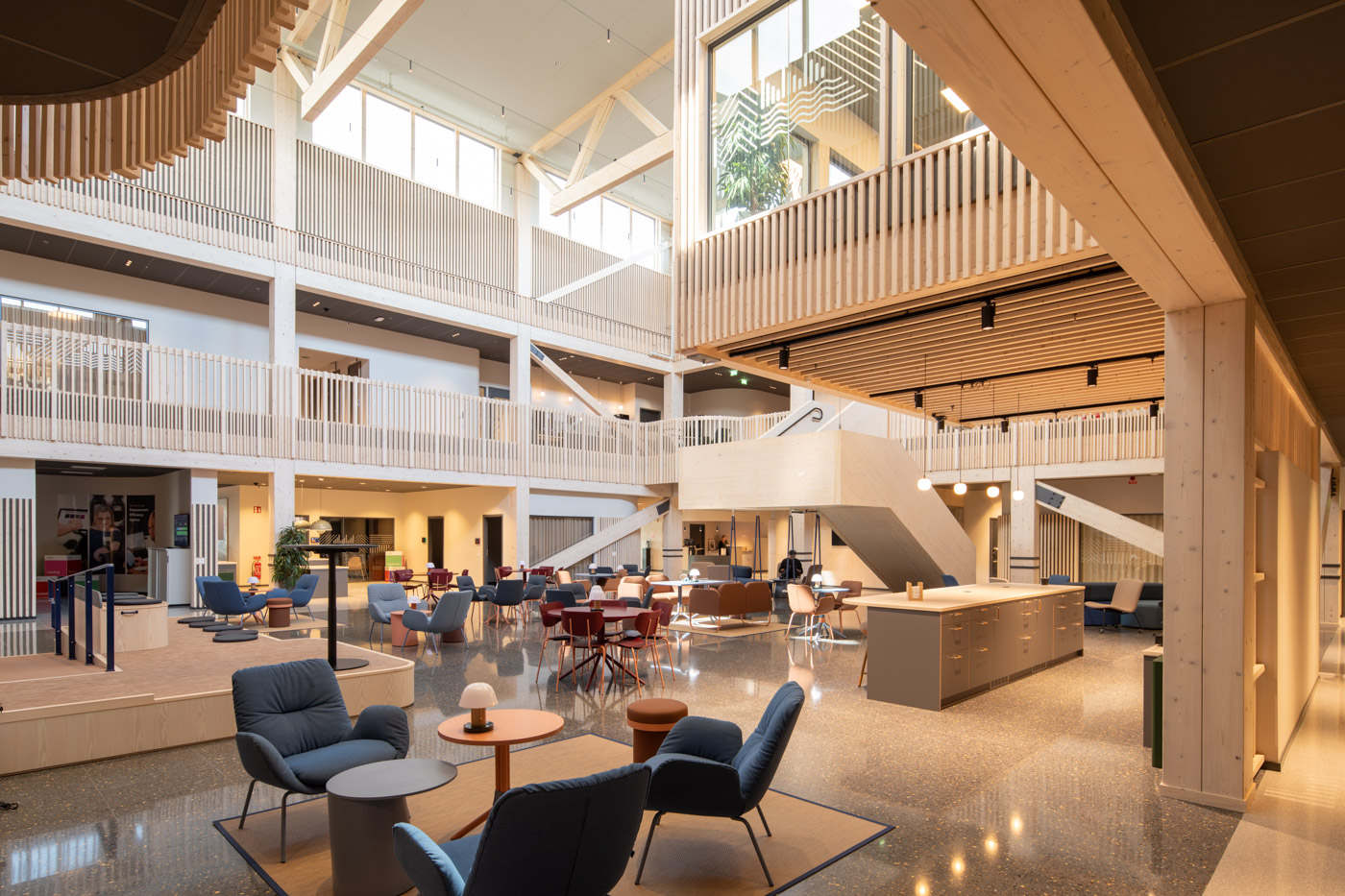 Ljustgård i modern kontorsbyggnad med fåtöljer i förgrund.