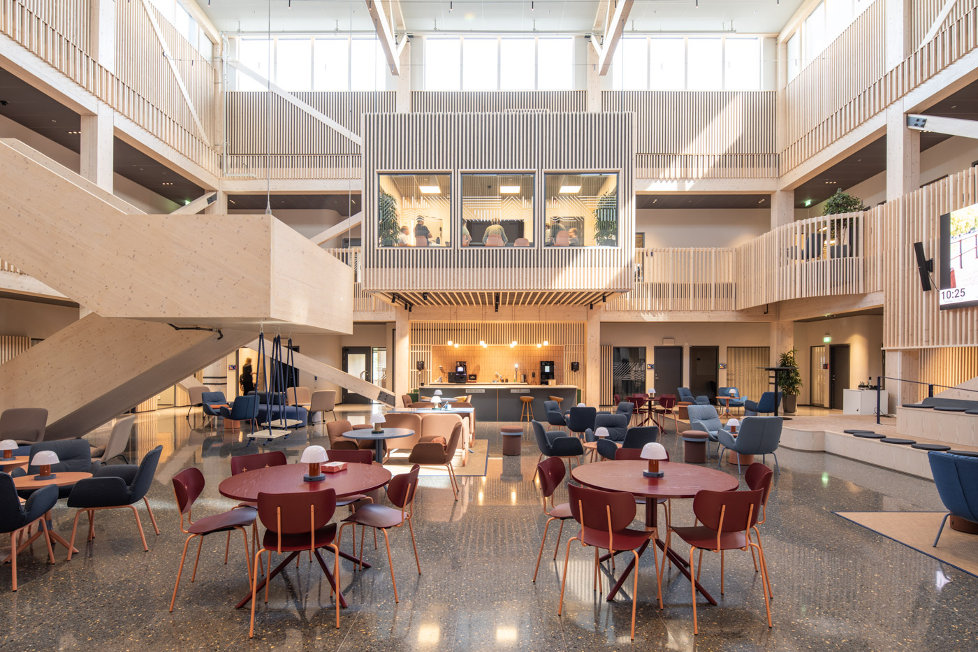 Bord och stolar i blått och vinrött i modern kontorsbyggnad.