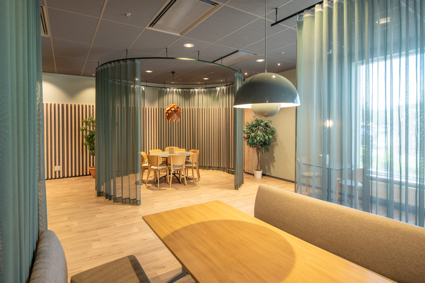 Sittytor i kontorslokal med tunna draperier i blått.