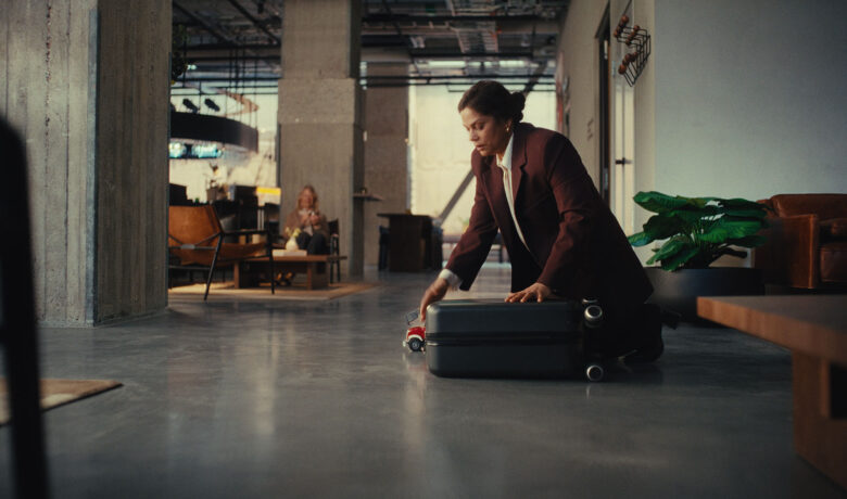 Person i kavaj packar en resväska på golvet i en modern hotellobby