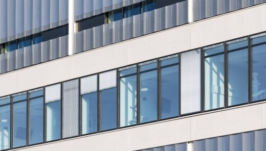 Modern kontorsfasad med stora glasfönster och vertikala metallpaneler.