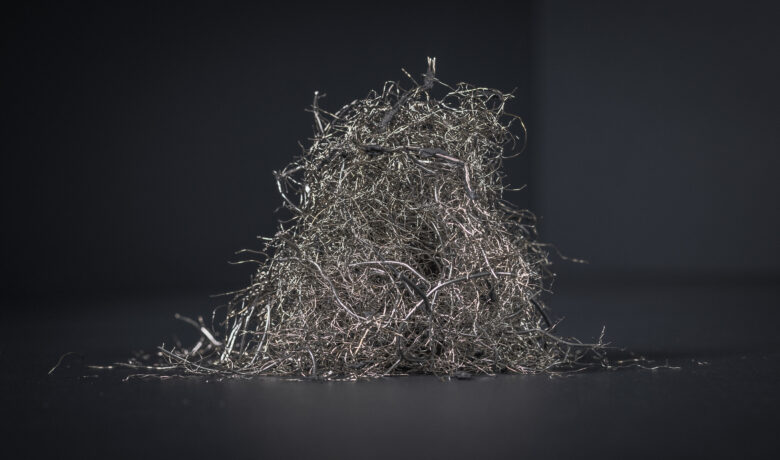 Ett konstnärliogt foto av en hög tunn silverfärgad metalltråd från återvunna däck mot svart bakgrund