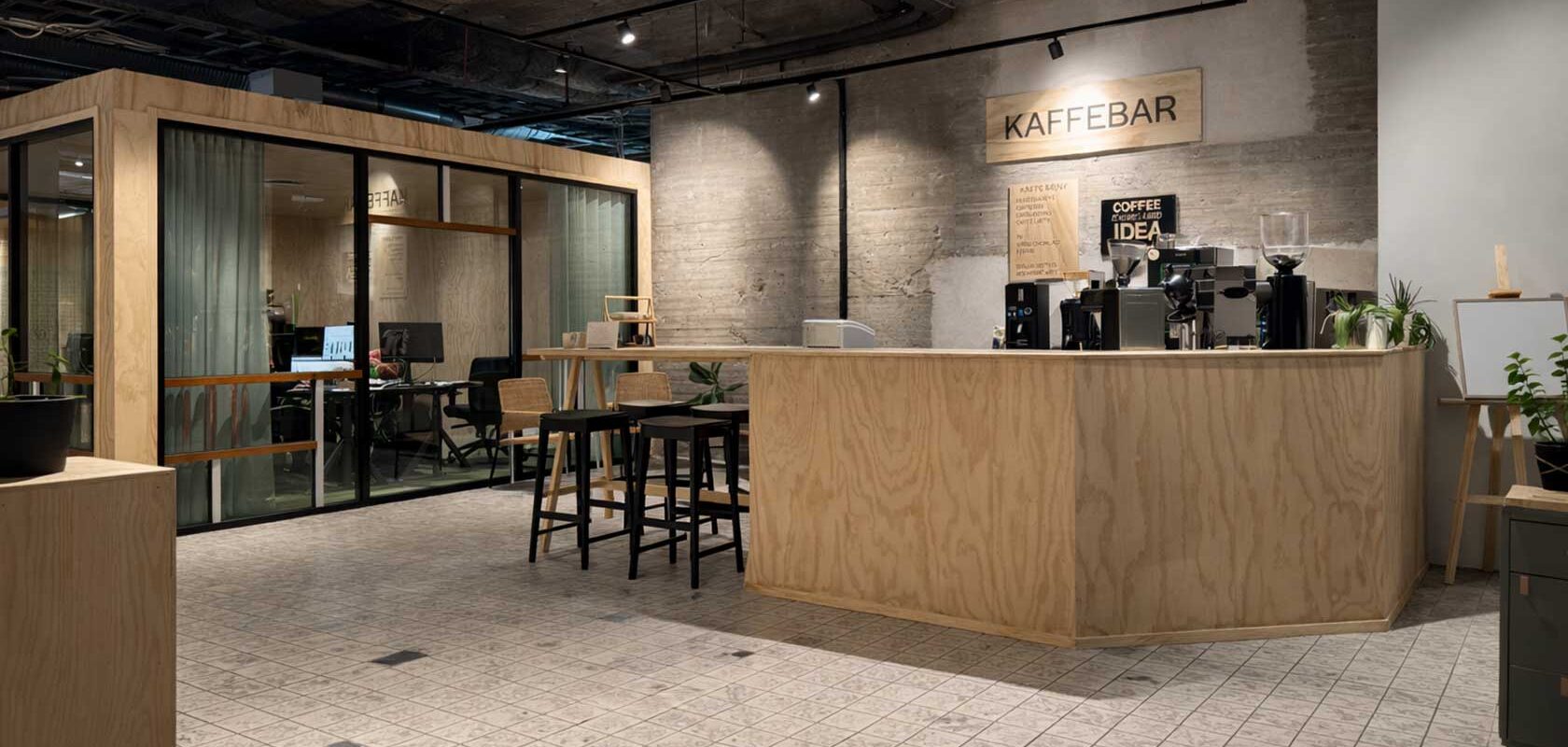 Modern kaffebar i kontorslobby med träbar, espressomaskin och sittplatser