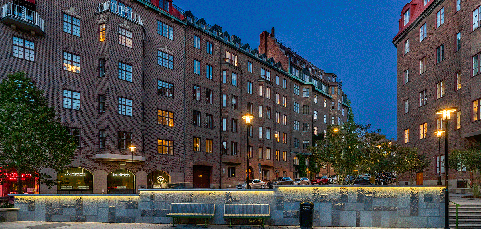 Flerbostadshus i äldre välbehållen arkitektur, bruna tegelfasader med modern dagvattenlösning och vackra parkbänkar.